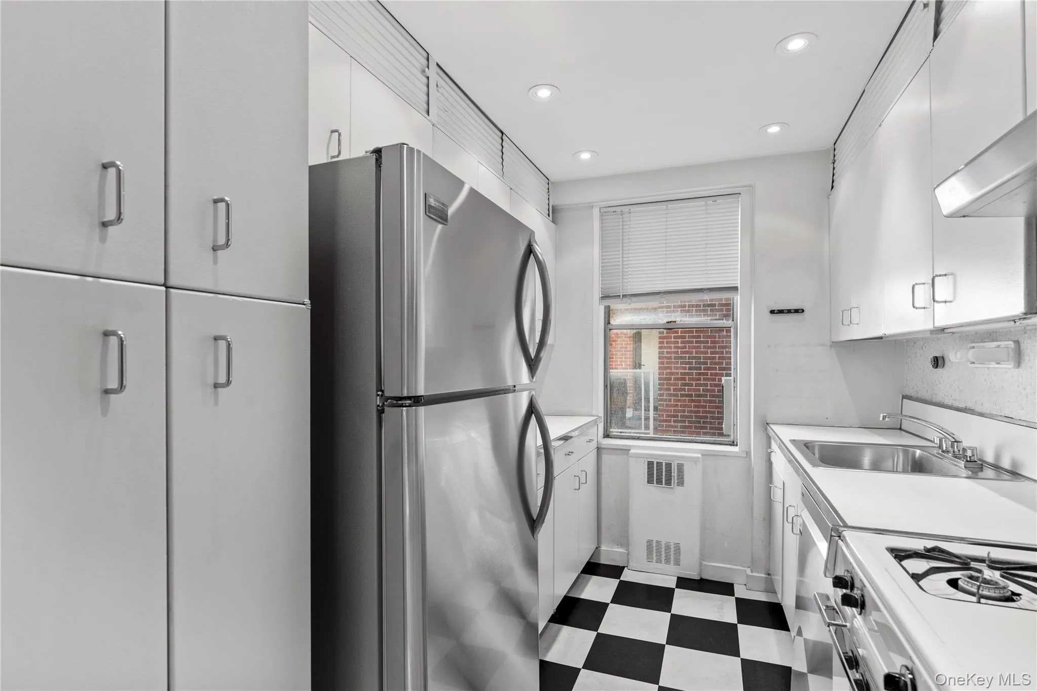Kitchen with radiator, dark floors, white gas range oven, freestanding refrigerator, and a sink Kitchen with radiator, dark floors, white gas range oven, freestanding refrigerator, and a sink