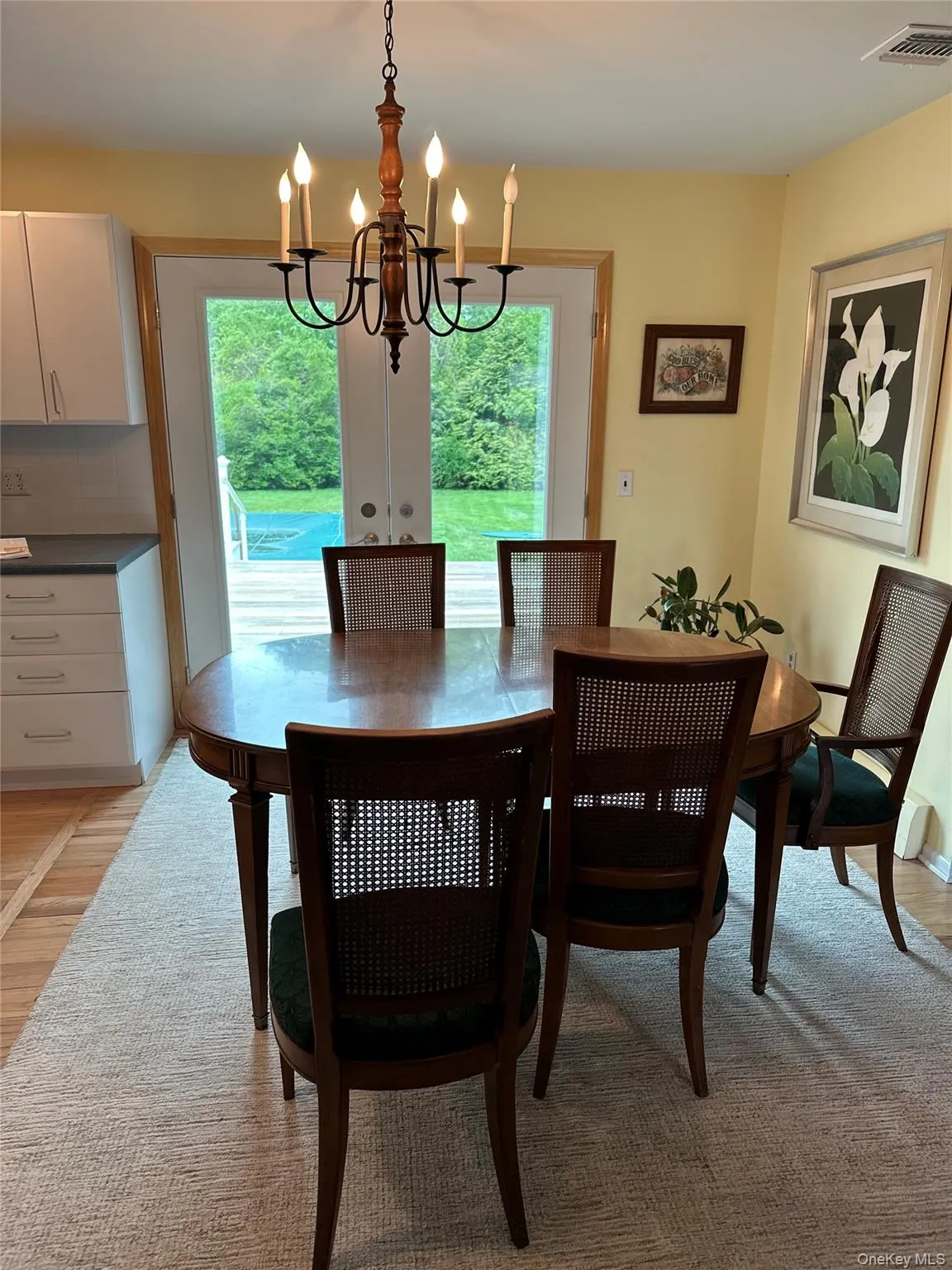 Dining area with an inviting chandelier, light wood-style flooring, and visible vents Dining area with an inviting chandelier, light wood-style flooring, and visible vents