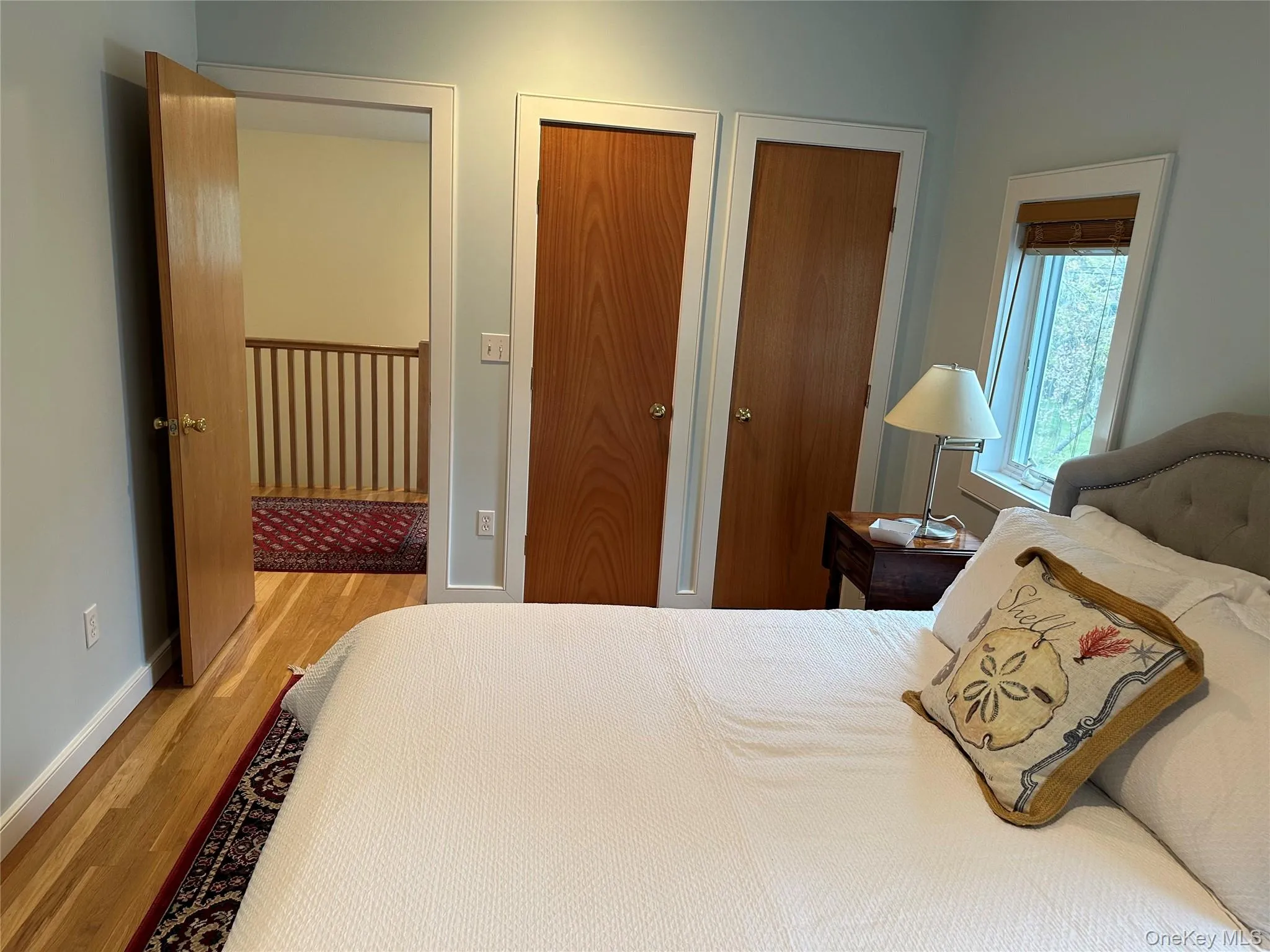 Bedroom featuring wood finished floors, two closets, and baseboards Bedroom featuring wood finished floors, two closets, and baseboards