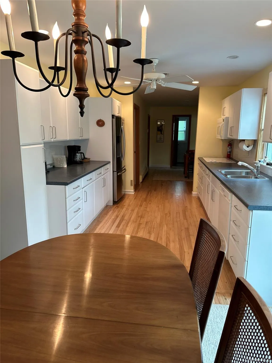 Kitchen featuring dark countertops, white appliances, white cabinetry, and a sink Kitchen featuring dark countertops, white appliances, white cabinetry, and a sink