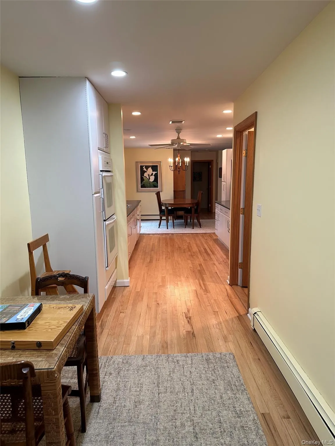 Hallway with light wood finished floors, a baseboard radiator, and recessed lighting Hallway with light wood finished floors, a baseboard radiator, and recessed lighting