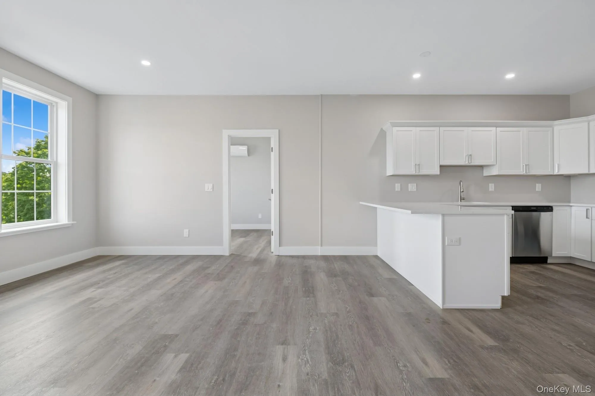 Kitchen featuring dishwasher, light countertops, wood finished floors, white cabinets, and recessed lighting Kitchen featuring dishwasher, light countertops, wood finished floors, white cabinets, and recessed lighting