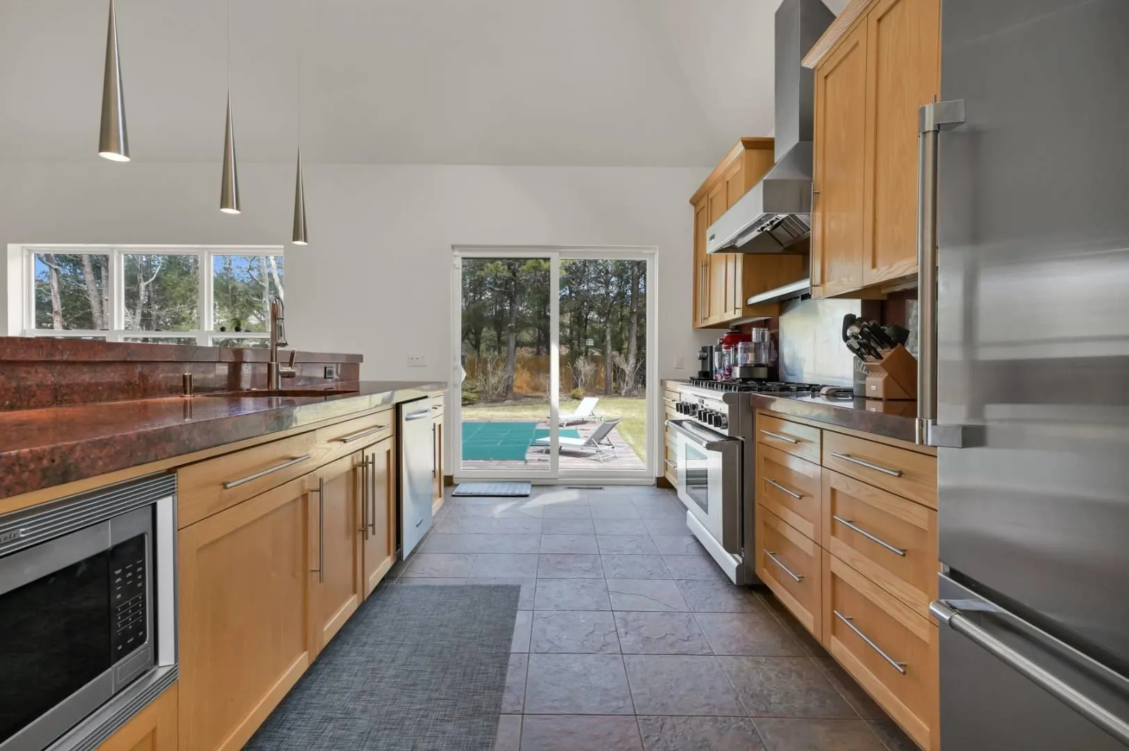 Kitchen with stainless steel appliances, plenty of natural light, a sink, and wall chimney range hood Kitchen with stainless steel appliances, plenty of natural light, a sink, and wall chimney range hood