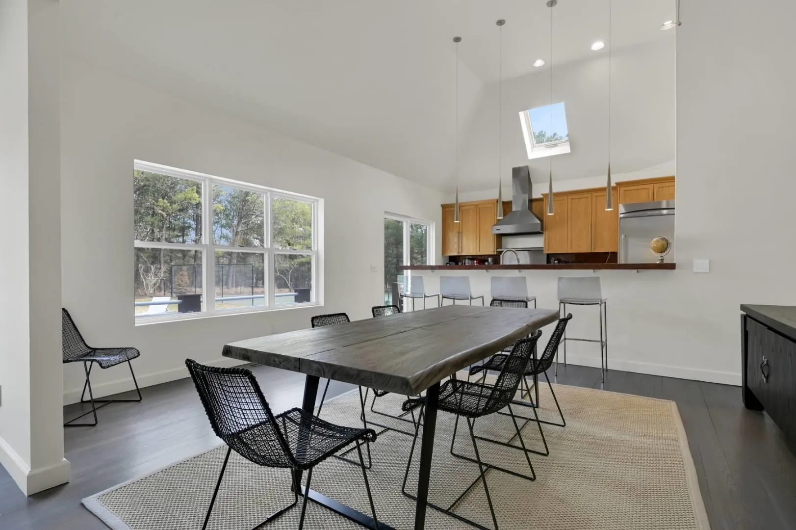 Dining space featuring a skylight, baseboards, high vaulted ceiling, and dark wood finished floors Dining space featuring a skylight, baseboards, high vaulted ceiling, and dark wood finished floors