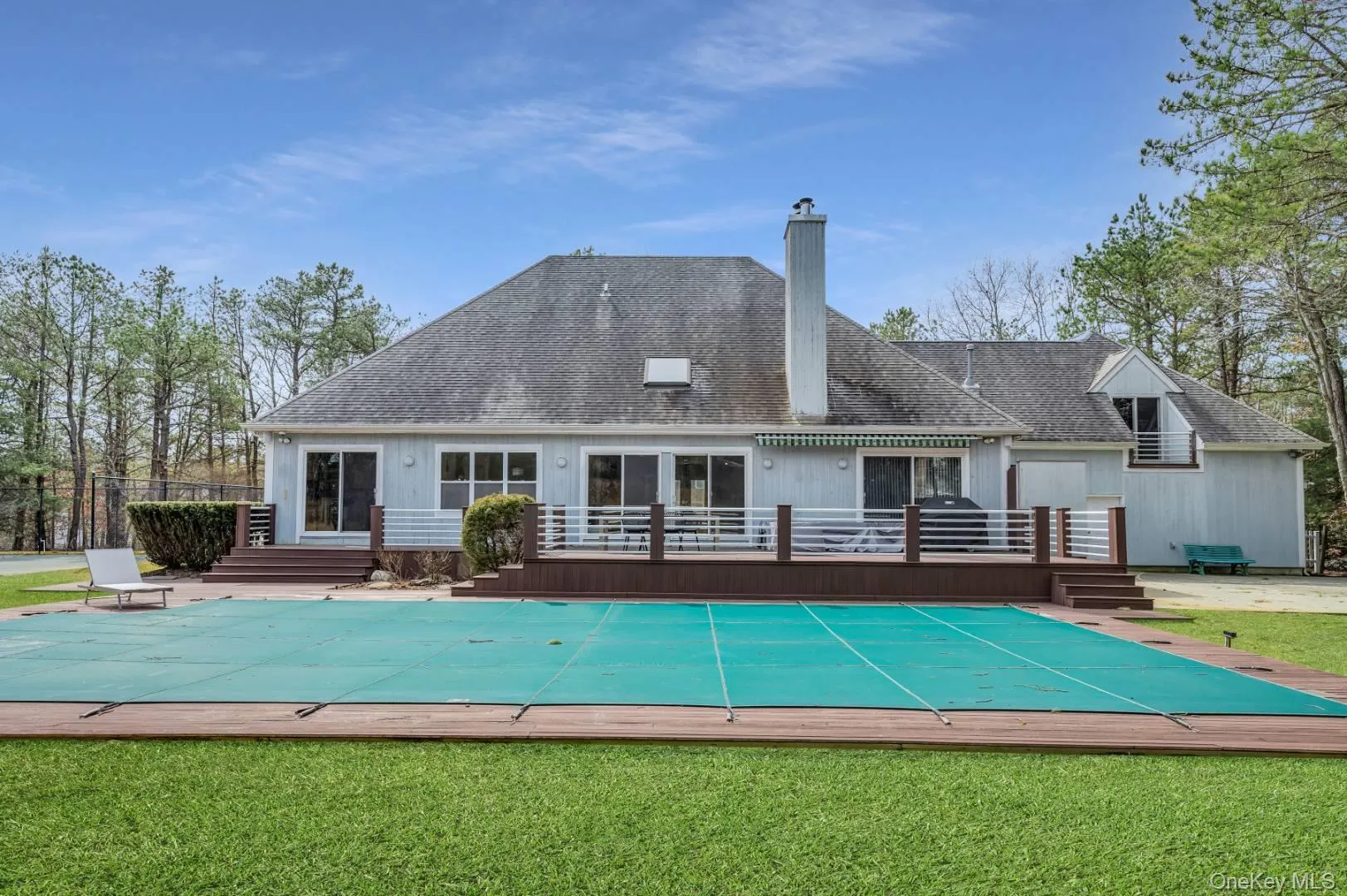 Back of house with a yard, a chimney, a fenced in pool, and a wooden deck Back of house with a yard, a chimney, a fenced in pool, and a wooden deck
