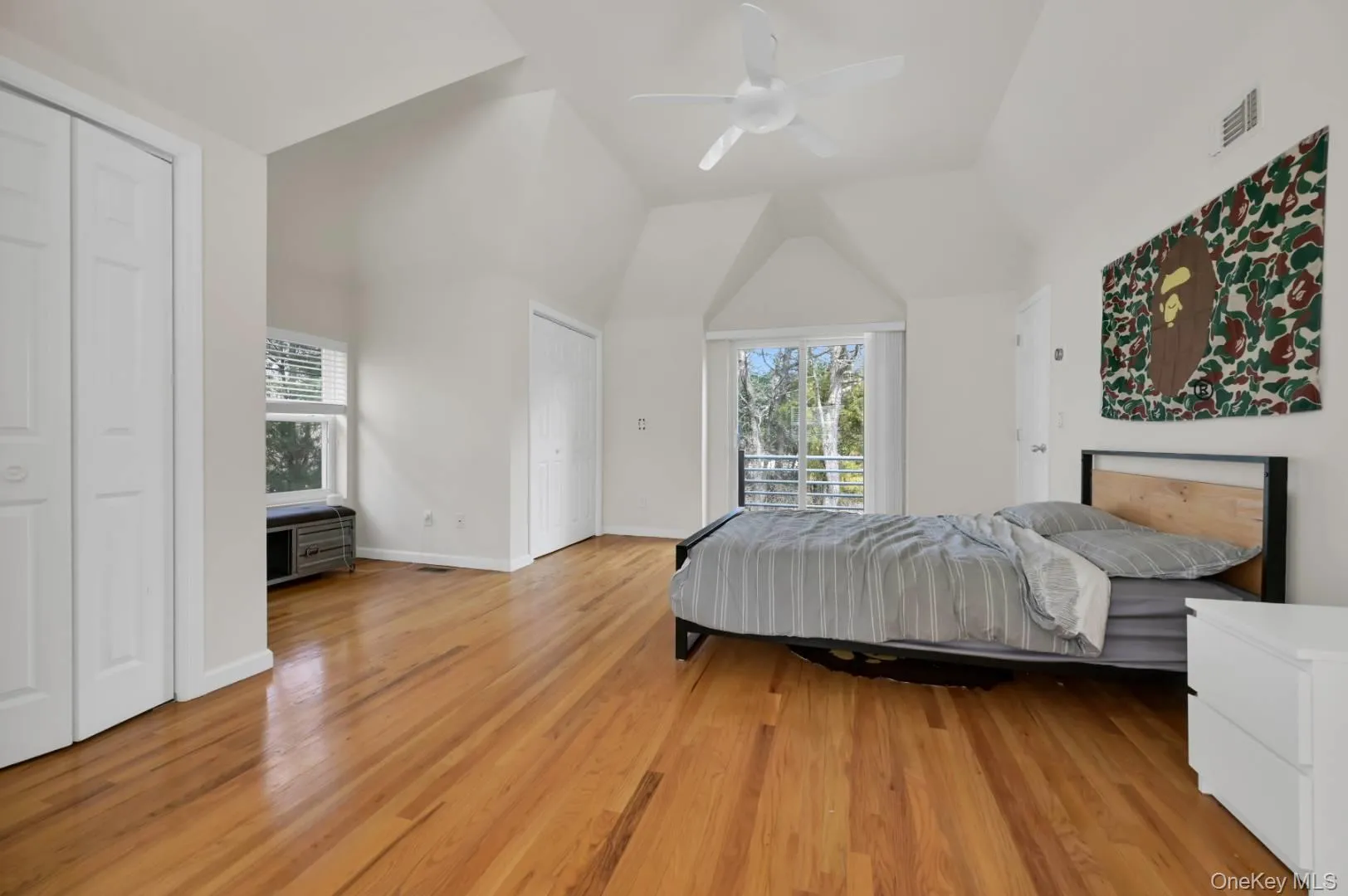 Bedroom featuring light wood-style floors, visible vents, vaulted ceiling, and baseboards Bedroom featuring light wood-style floors, visible vents, vaulted ceiling, and baseboards