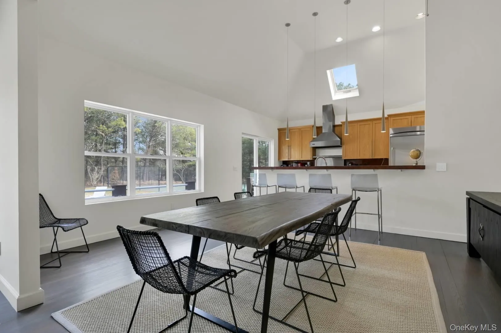Dining space featuring a skylight, baseboards, high vaulted ceiling, and dark wood finished floors Dining space featuring a skylight, baseboards, high vaulted ceiling, and dark wood finished floors