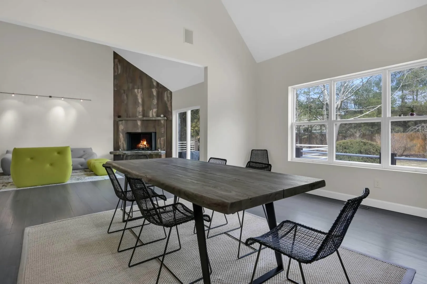 Dining area featuring a large fireplace, high vaulted ceiling, wood finished floors, and baseboards Dining area featuring a large fireplace, high vaulted ceiling, wood finished floors, and baseboards