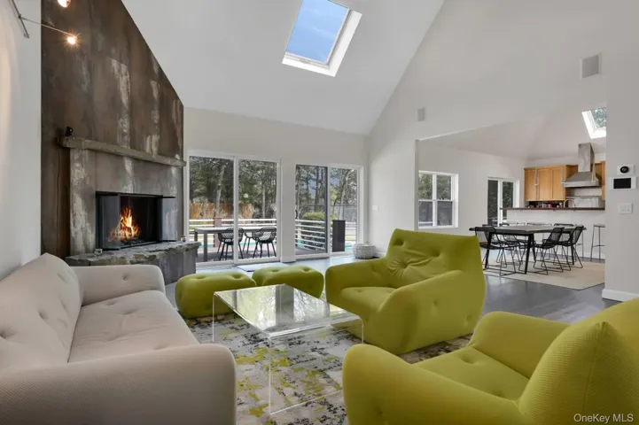 Living area featuring a skylight, visible vents, a premium fireplace, wood finished floors, and high vaulted ceiling