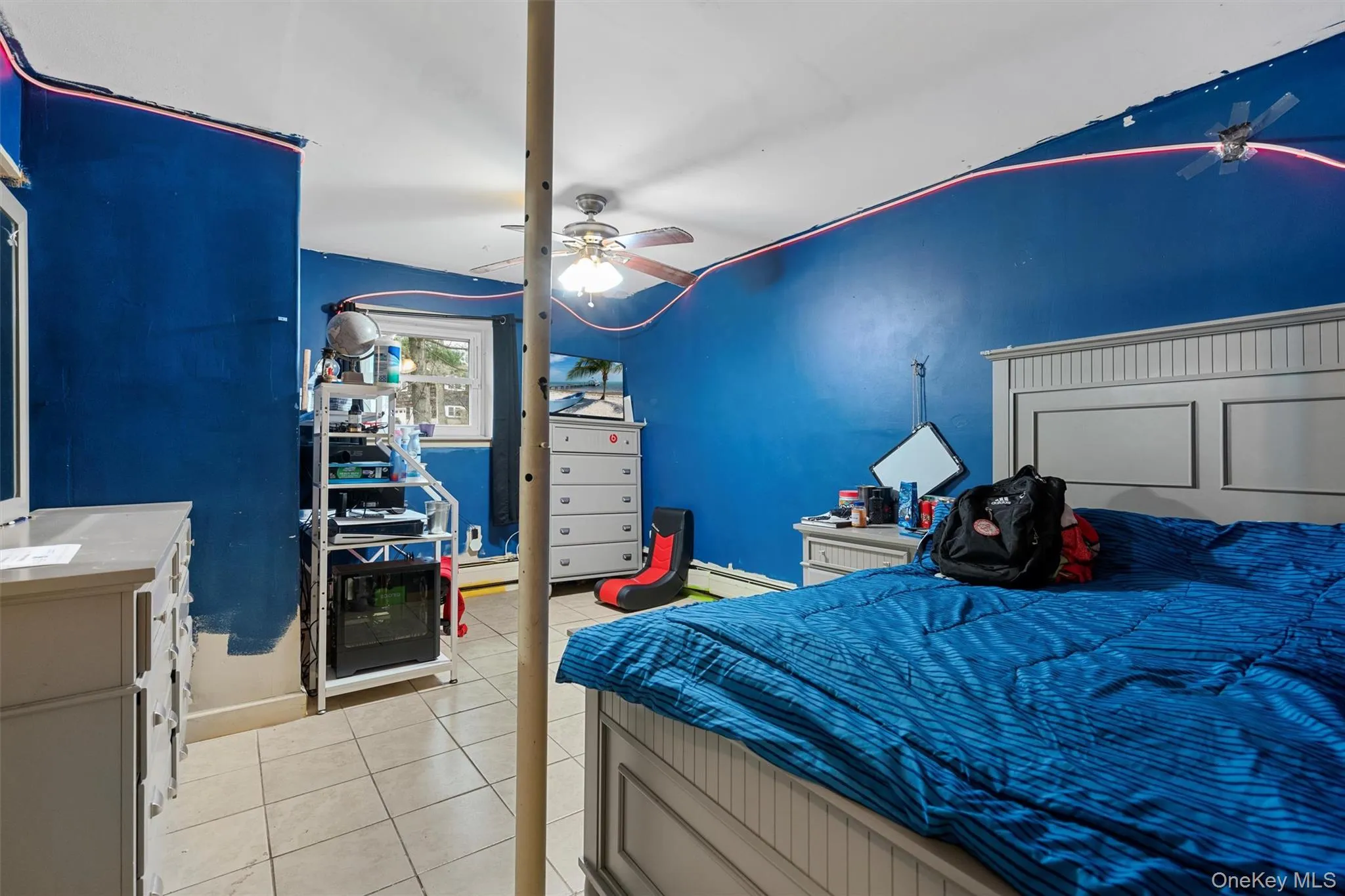 Bedroom featuring light tile patterned flooring, a baseboard heating unit, and a ceiling fan Bedroom featuring light tile patterned flooring, a baseboard heating unit, and a ceiling fan