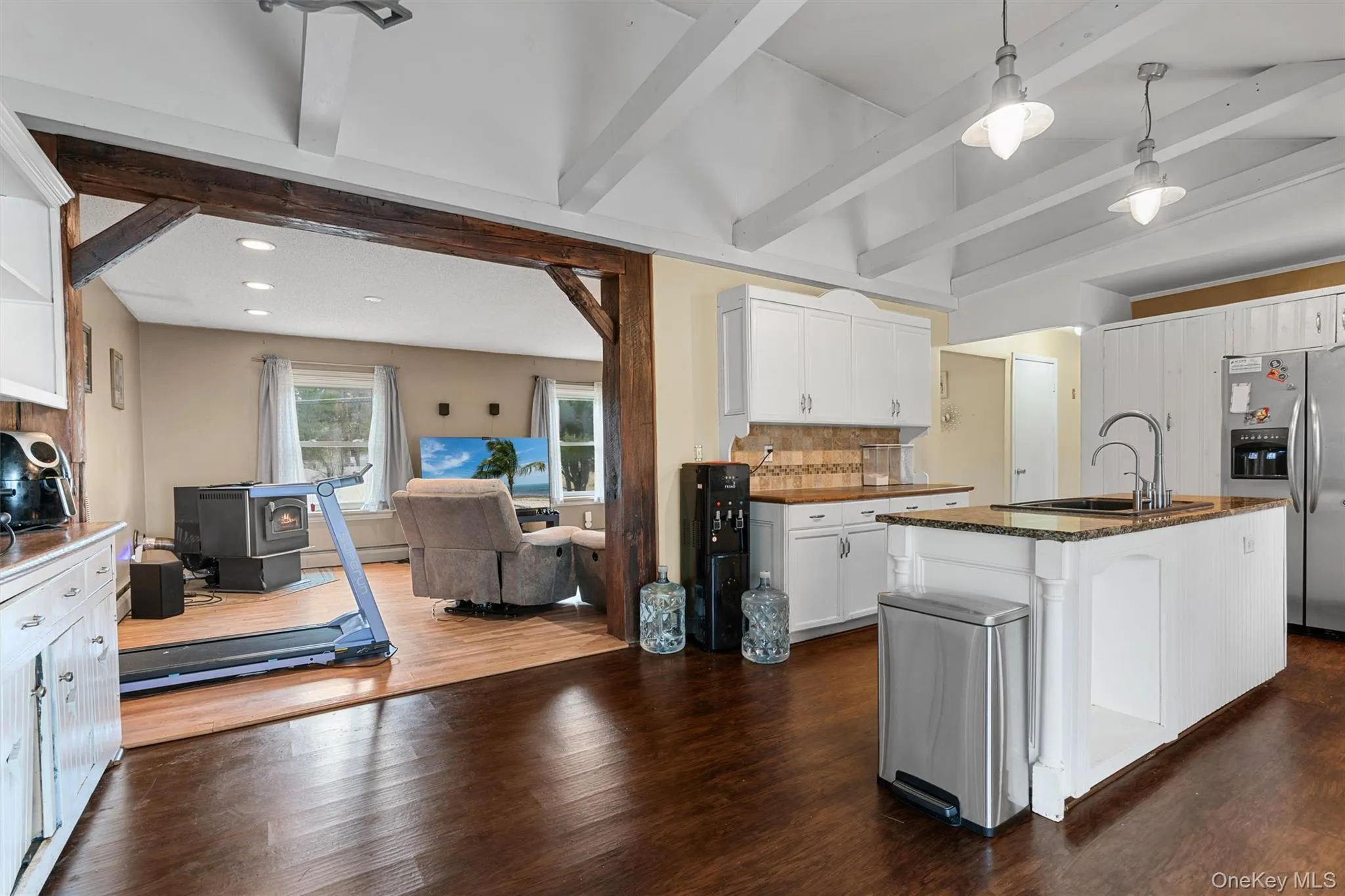 Kitchen featuring tasteful backsplash, open floor plan, a wood stove, stainless steel fridge, and a sink Kitchen featuring tasteful backsplash, open floor plan, a wood stove, stainless steel fridge, and a sink