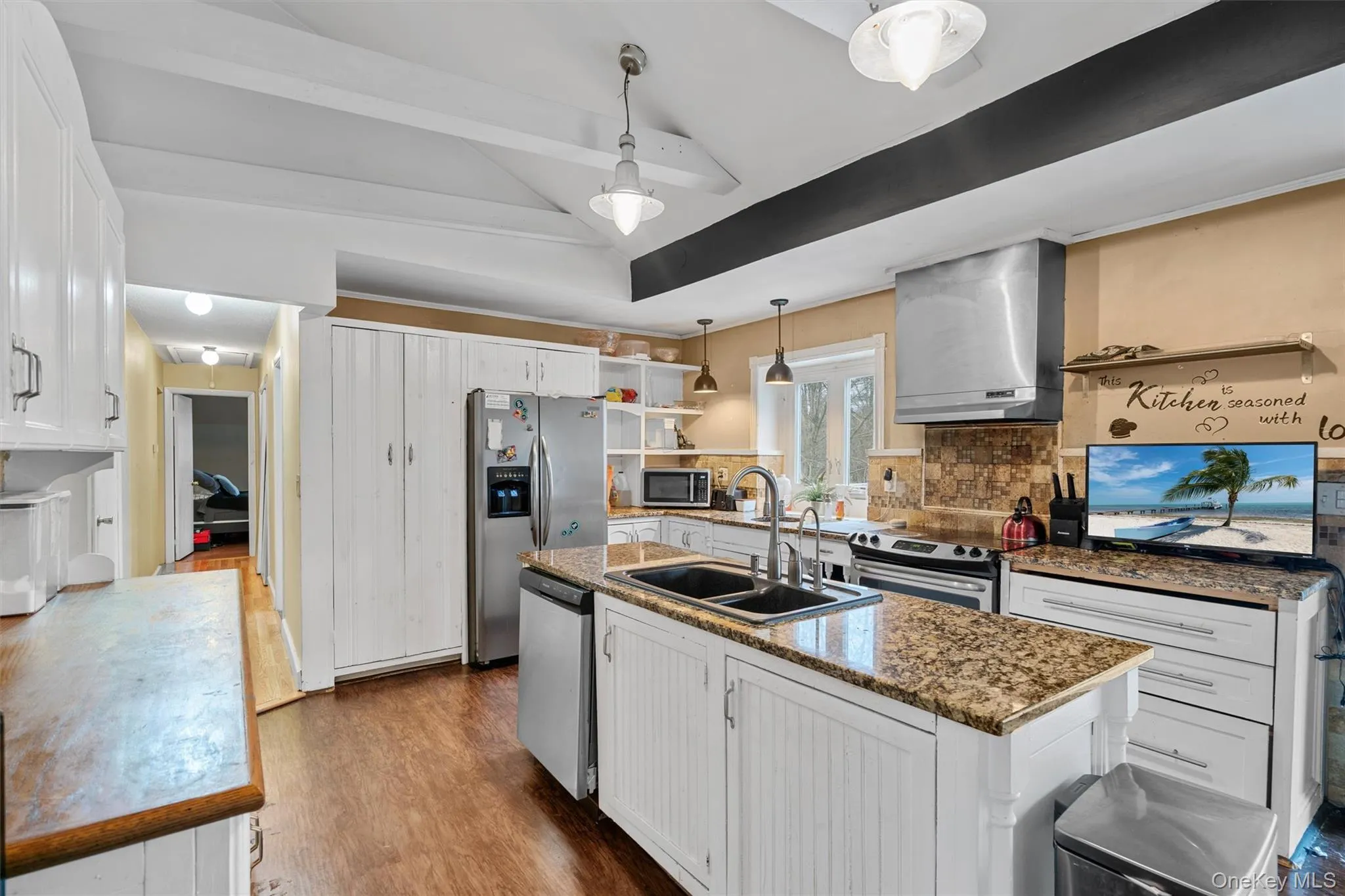 Kitchen with white cabinets, appliances with stainless steel finishes, wall chimney range hood, and a sink Kitchen with white cabinets, appliances with stainless steel finishes, wall chimney range hood, and a sink