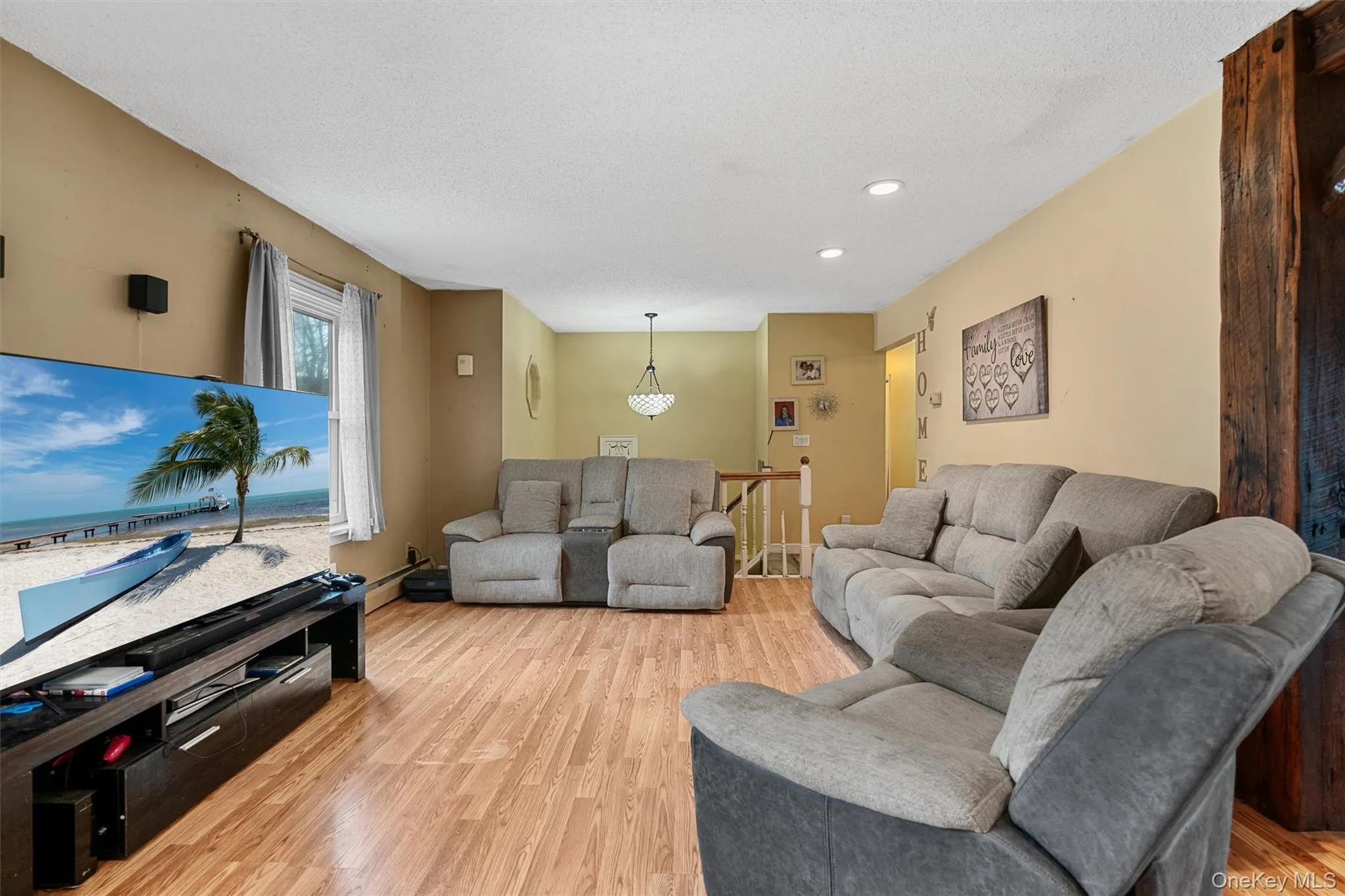 Living room featuring light wood-style flooring, recessed lighting, and a textured ceiling Living room featuring light wood-style flooring, recessed lighting, and a textured ceiling