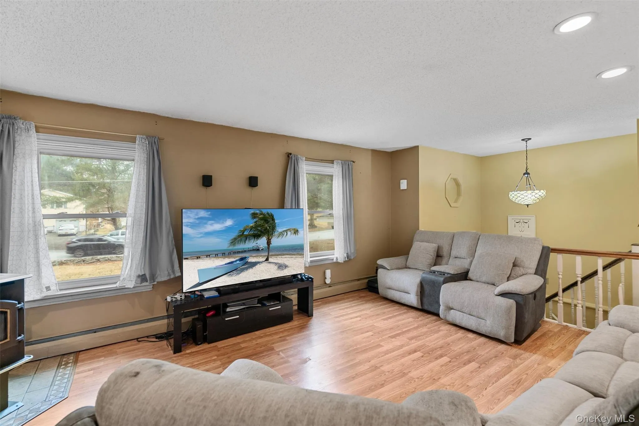 Living area with plenty of natural light, recessed lighting, a textured ceiling, and wood finished floors Living area with plenty of natural light, recessed lighting, a textured ceiling, and wood finished floors
