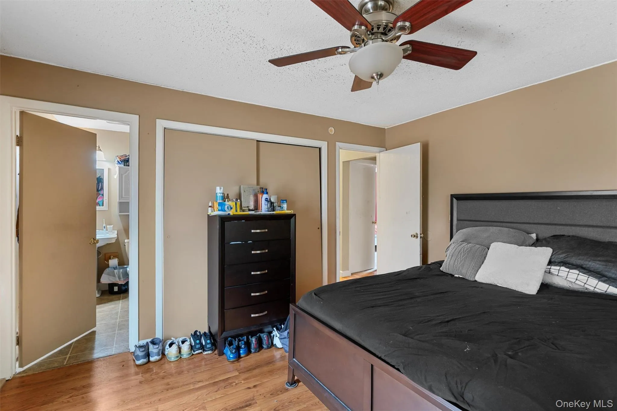 Bedroom with a ceiling fan, light wood-type flooring, a closet, and a textured ceiling Bedroom with a ceiling fan, light wood-type flooring, a closet, and a textured ceiling