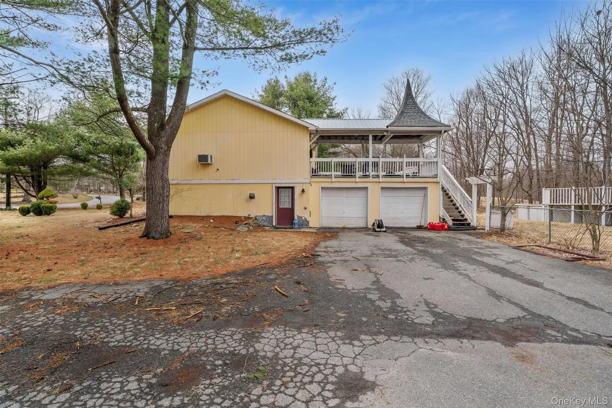 View of side of home featuring stairway, fence, driveway, a porch, and a garage View of side of home featuring stairway, fence, driveway, a porch, and a garage