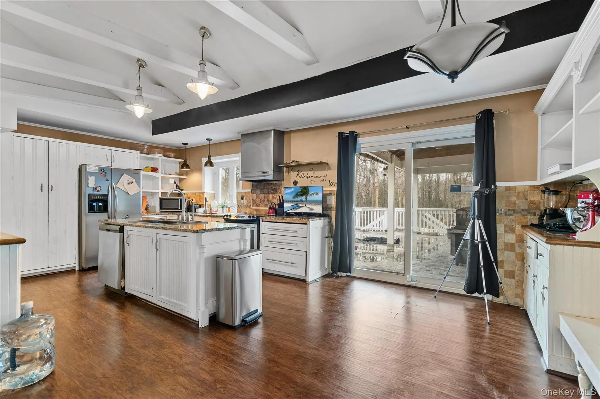 Kitchen featuring open shelves, a sink, dark wood-style floors, stainless steel appliances, and hanging light fixtures Kitchen featuring open shelves, a sink, dark wood-style floors, stainless steel appliances, and hanging light fixtures