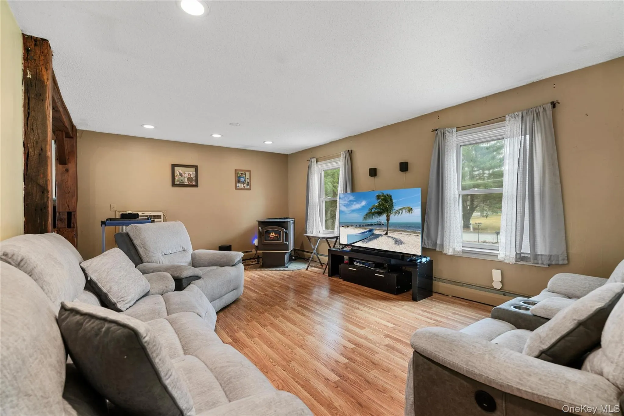 Living area featuring recessed lighting, a baseboard heating unit, light wood-style floors, and a wood stove Living area featuring recessed lighting, a baseboard heating unit, light wood-style floors, and a wood stove