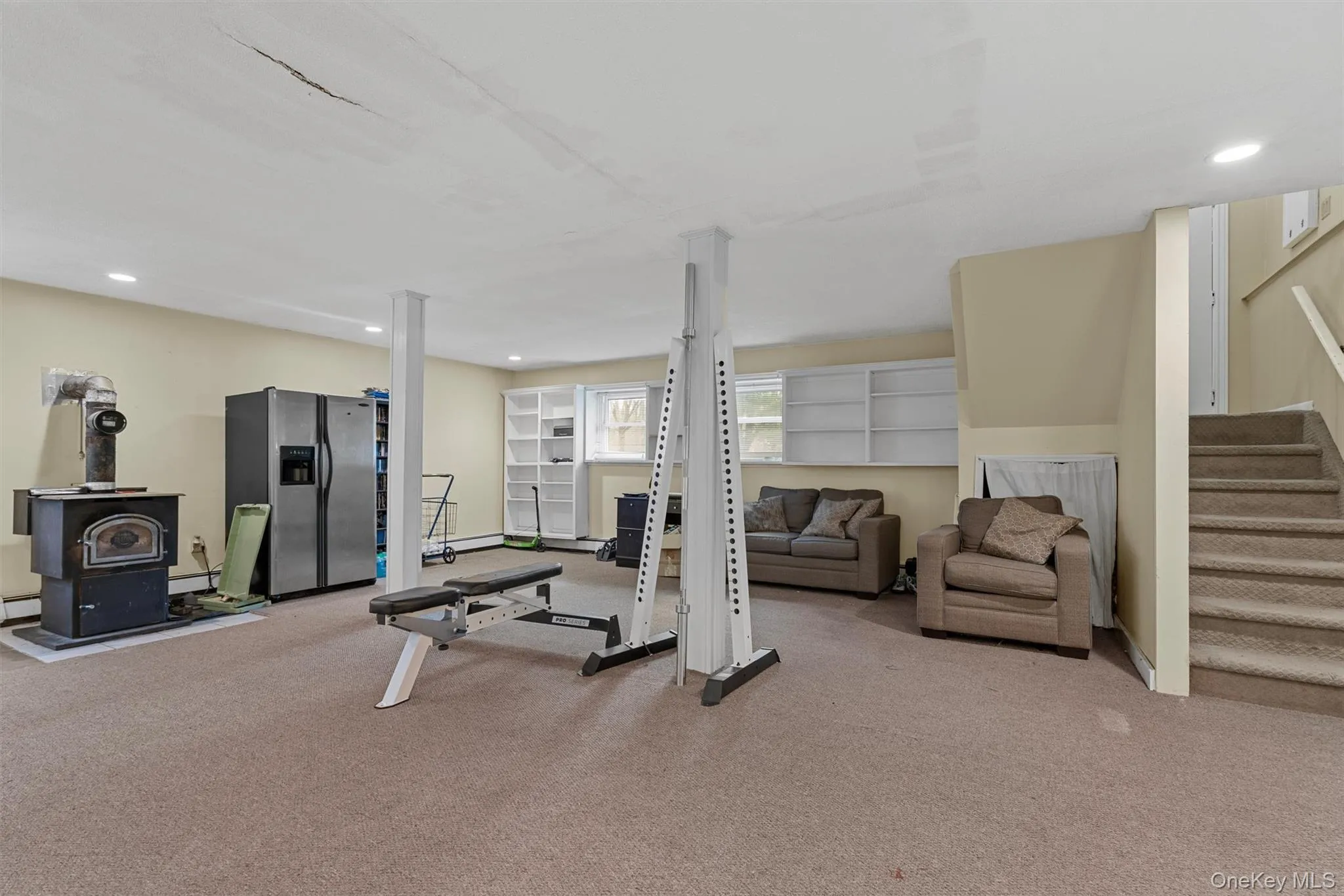 Exercise area featuring recessed lighting, a wood stove, and carpet floors Exercise area featuring recessed lighting, a wood stove, and carpet floors