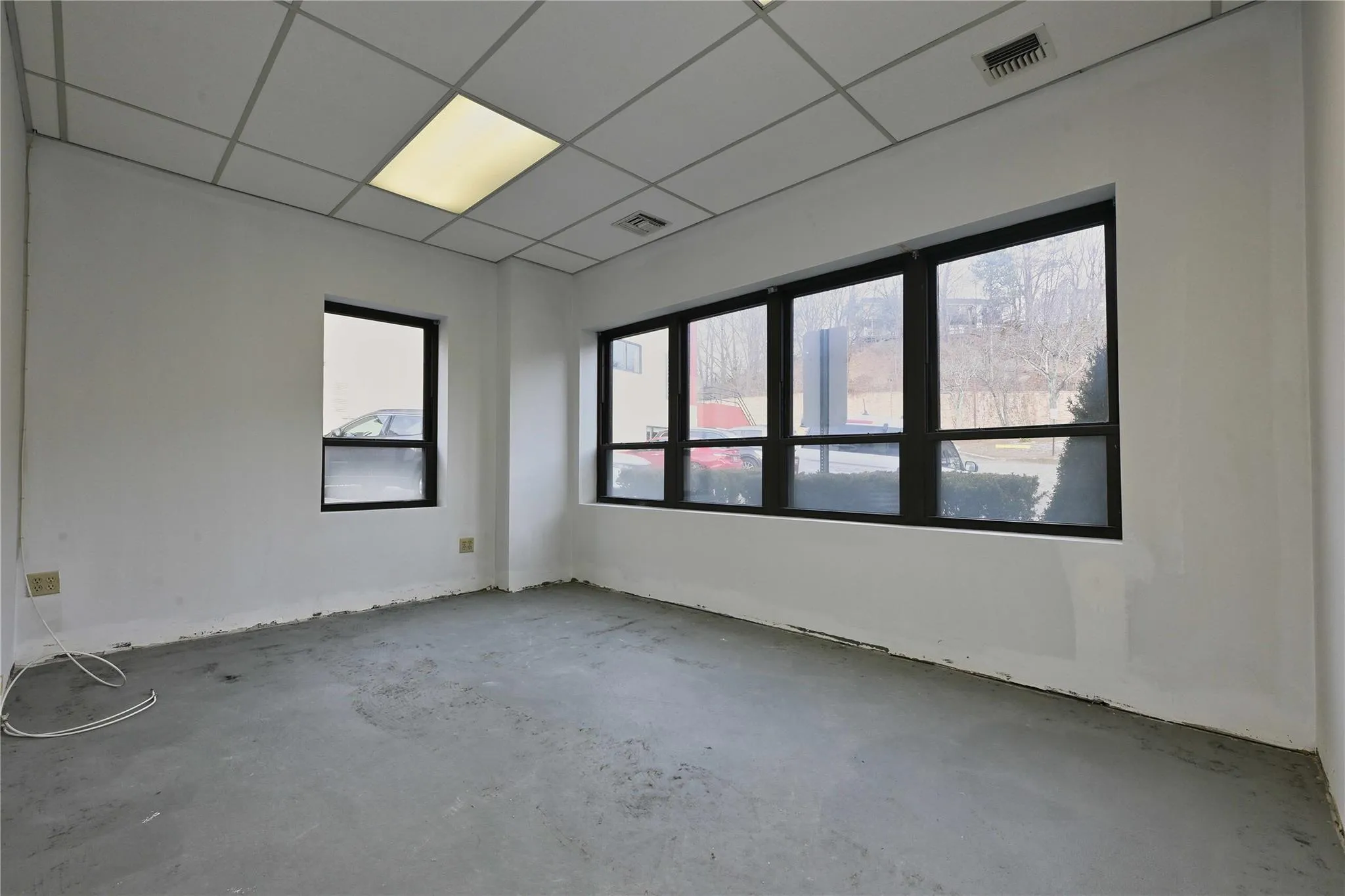 Unfurnished room with a drop ceiling, visible vents, and unfinished concrete flooring Unfurnished room with a drop ceiling, visible vents, and unfinished concrete flooring