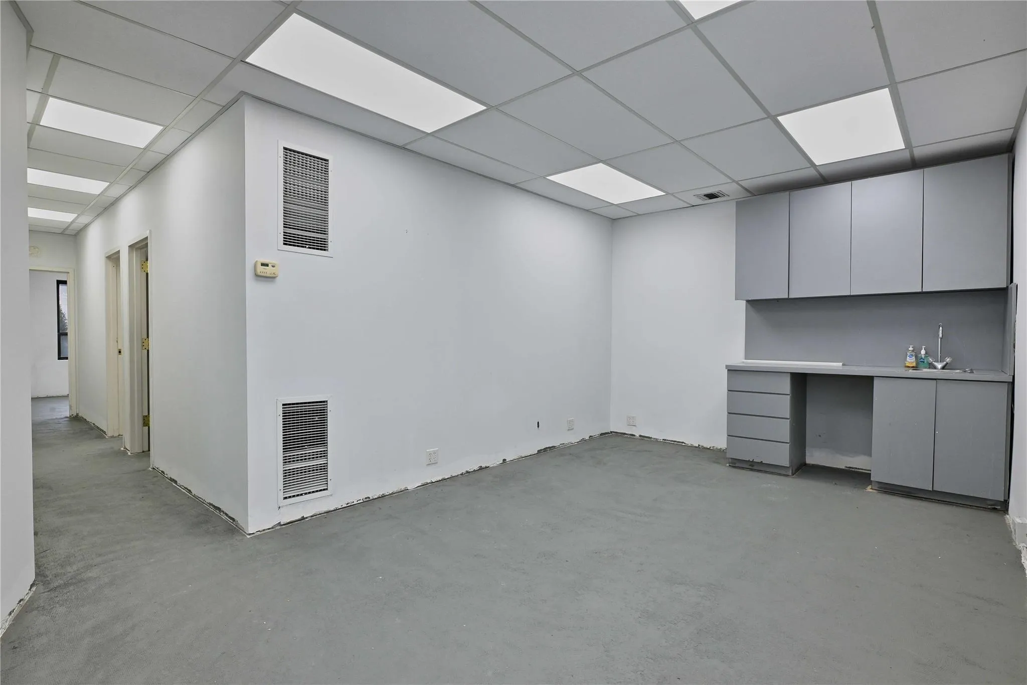 Unfurnished office featuring concrete flooring, a drop ceiling, and visible vents Unfurnished office featuring concrete flooring, a drop ceiling, and visible vents