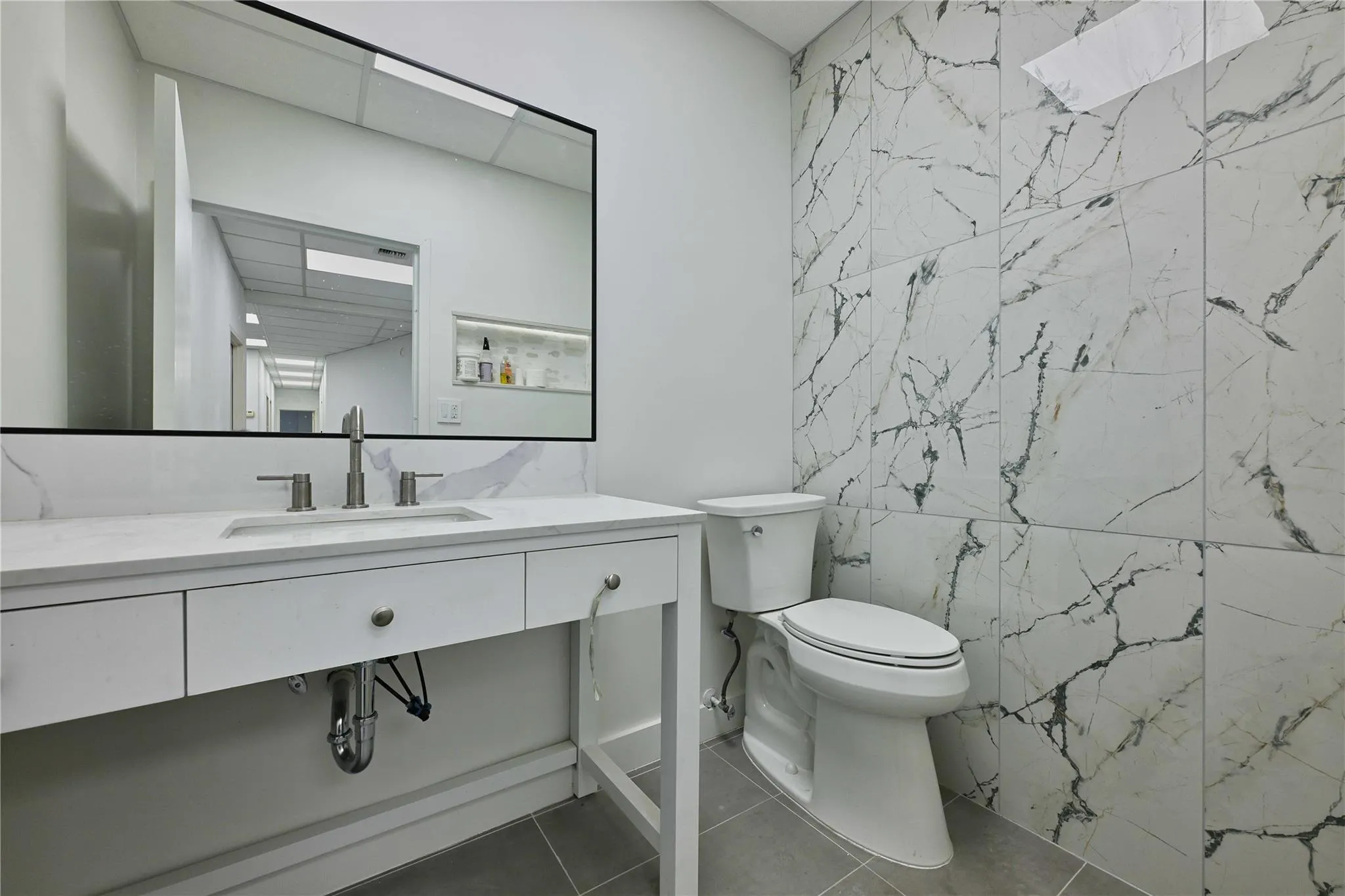 Bathroom featuring tile walls, vanity, toilet, and tile patterned floors Bathroom featuring tile walls, vanity, toilet, and tile patterned floors