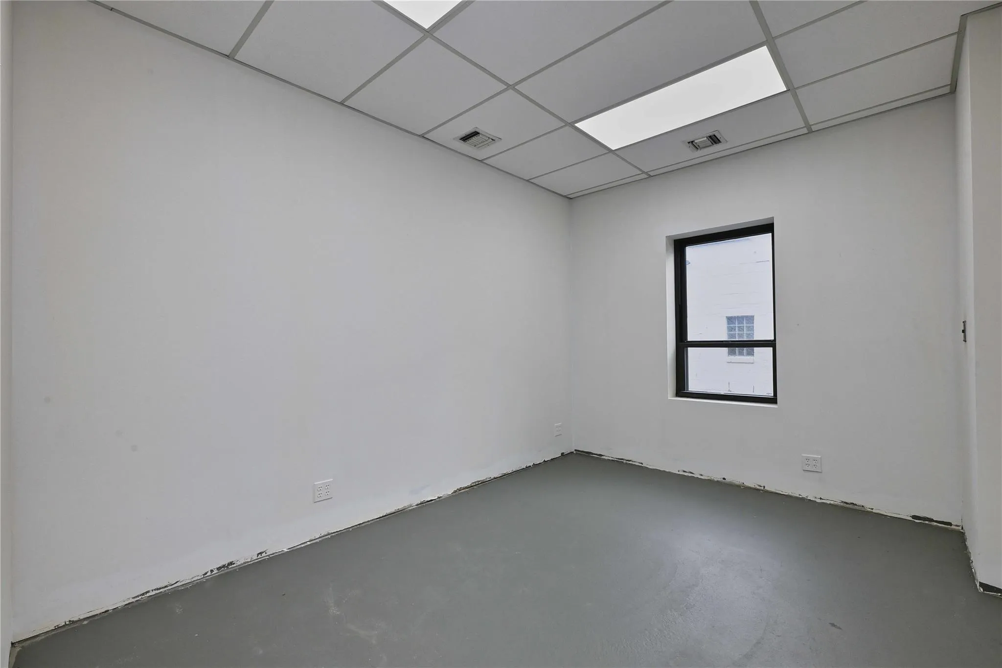 Unfurnished room featuring visible vents, concrete flooring, and a drop ceiling Unfurnished room featuring visible vents, concrete flooring, and a drop ceiling