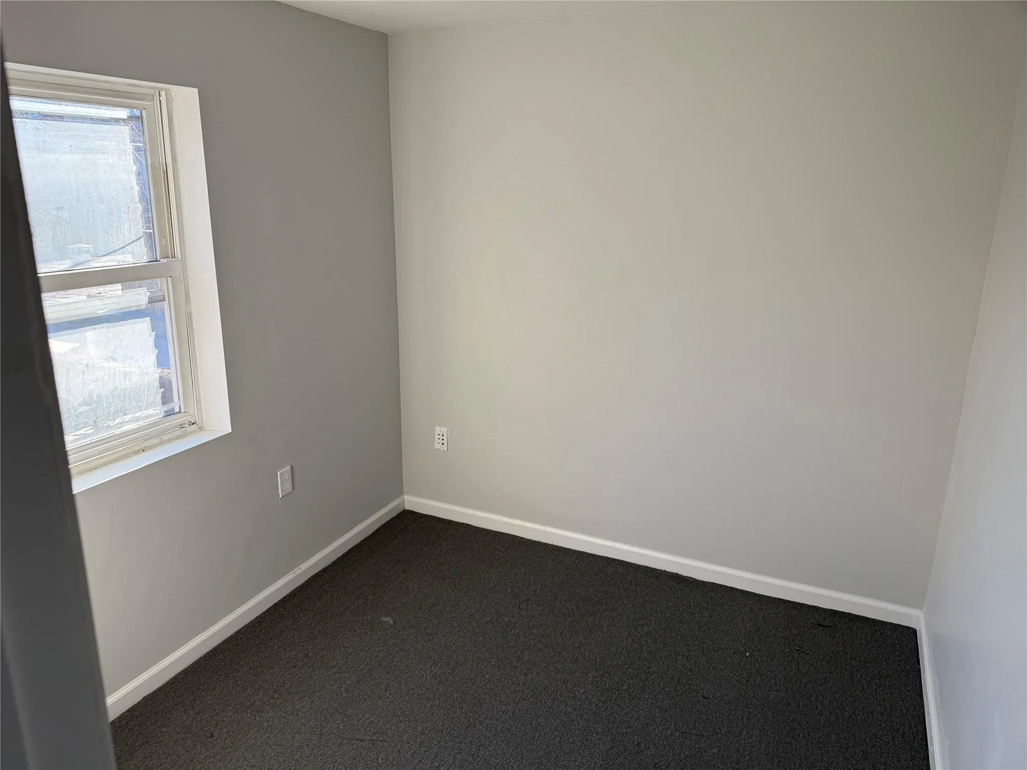 Unfurnished room featuring a healthy amount of sunlight, baseboards, and dark carpet Unfurnished room featuring a healthy amount of sunlight, baseboards, and dark carpet