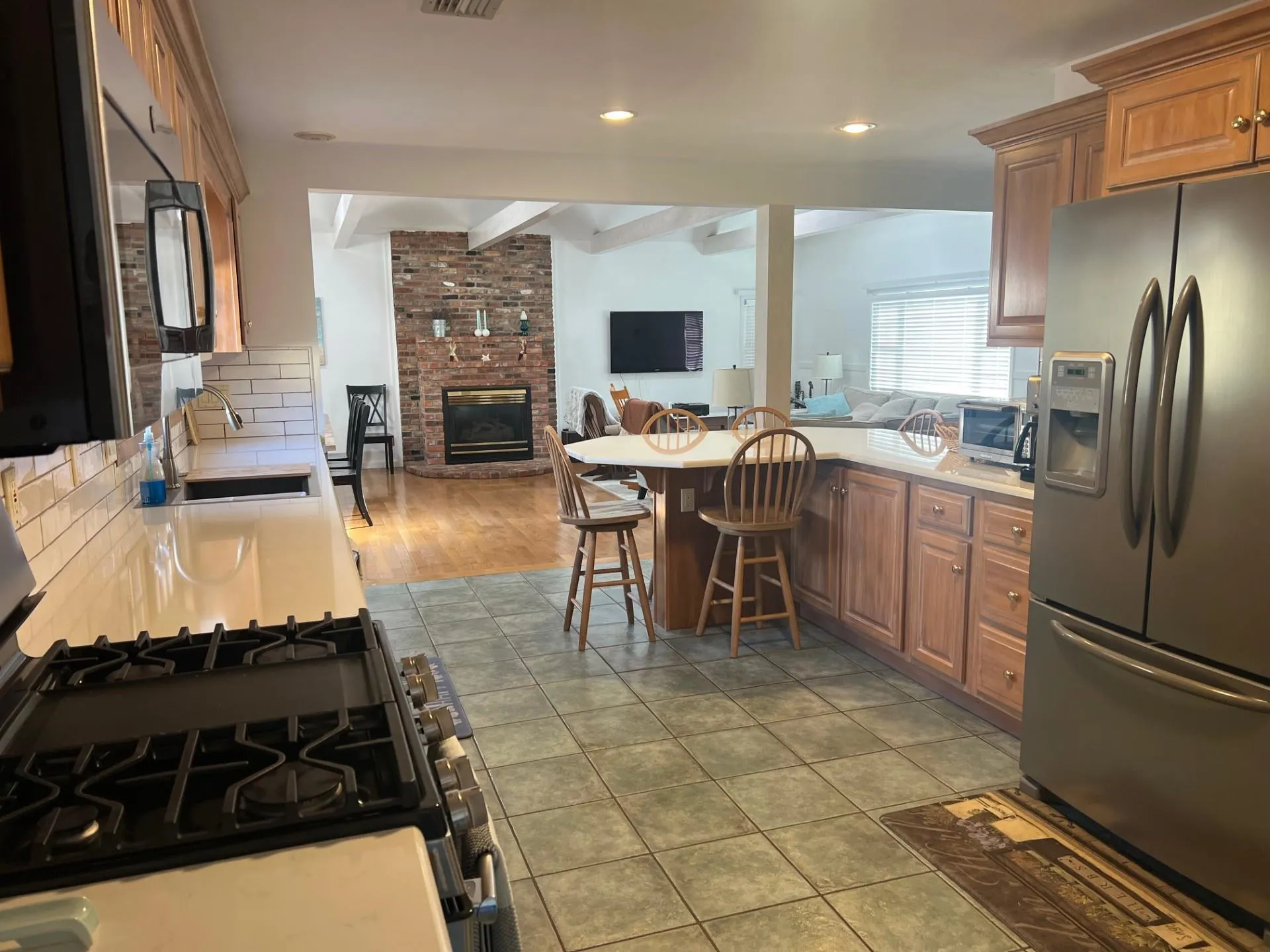Kitchen with a sink, a fireplace, open floor plan, stainless steel appliances, and decorative backsplash Kitchen with a sink, a fireplace, open floor plan, stainless steel appliances, and decorative backsplash