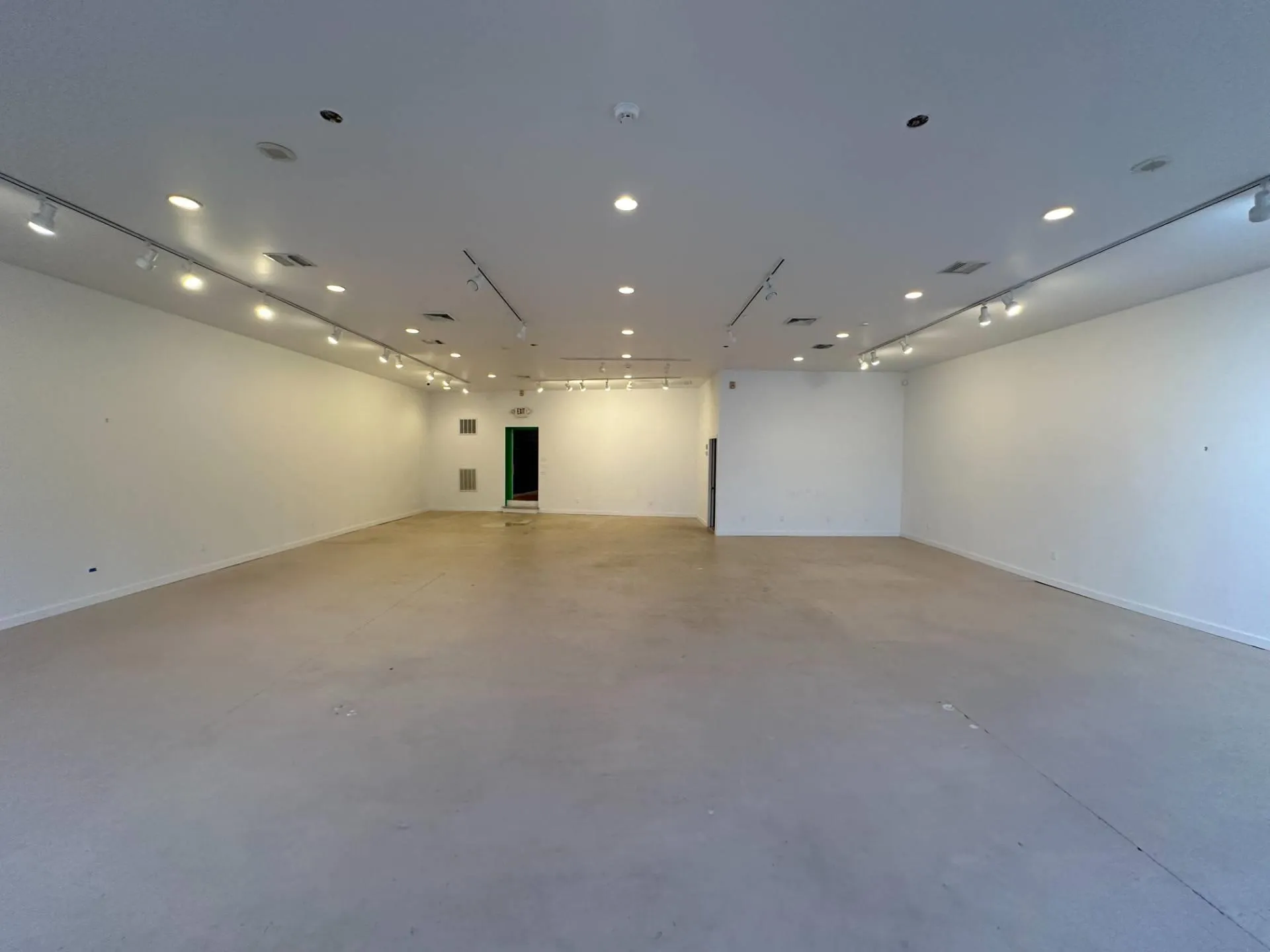 Unfurnished room featuring finished concrete floors, rail lighting, visible vents, and baseboards Unfurnished room featuring finished concrete floors, rail lighting, visible vents, and baseboards