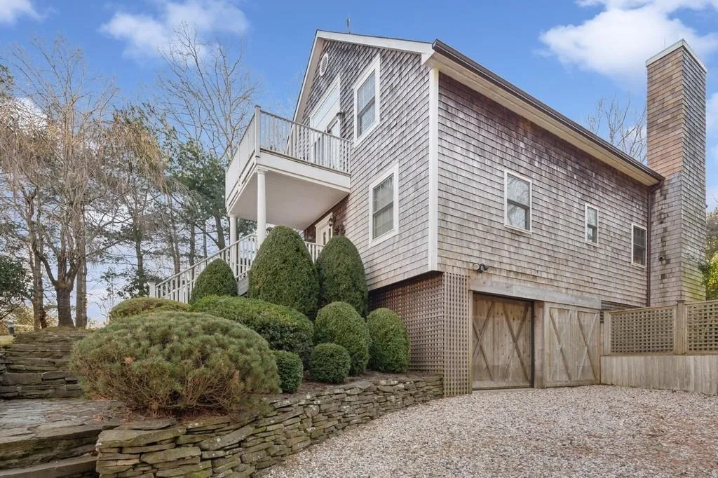 View of side of property featuring a garage, driveway, a chimney, and a balcony View of side of property featuring a garage, driveway, a chimney, and a balcony