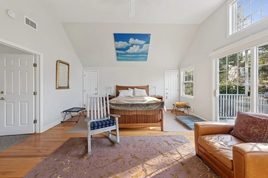 Bedroom with baseboards, visible vents, lofted ceiling, wood finished floors, and access to outside Bedroom with baseboards, visible vents, lofted ceiling, wood finished floors, and access to outside