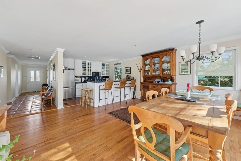 Dining area featuring crown molding, baseboards, a chandelier, and light wood-style floors Dining area featuring crown molding, baseboards, a chandelier, and light wood-style floors