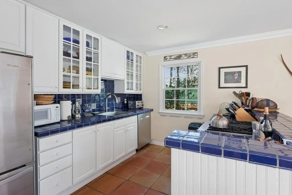 Kitchen with tile countertops, a sink, appliances with stainless steel finishes, decorative backsplash, and crown molding Kitchen with tile countertops, a sink, appliances with stainless steel finishes, decorative backsplash, and crown molding