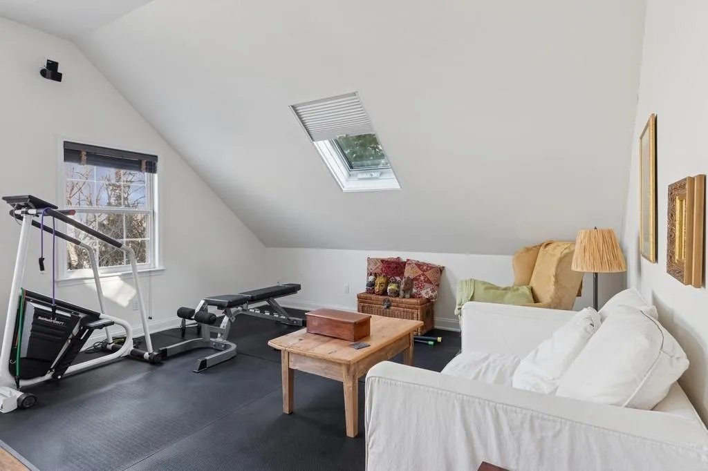 Exercise area featuring lofted ceiling with skylight and baseboards Exercise area featuring lofted ceiling with skylight and baseboards