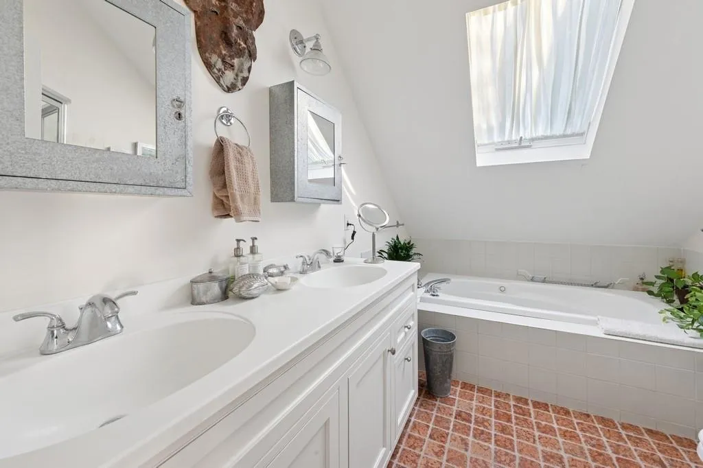 Full bath featuring vaulted ceiling, a garden tub, a sink, and double vanity Full bath featuring vaulted ceiling, a garden tub, a sink, and double vanity
