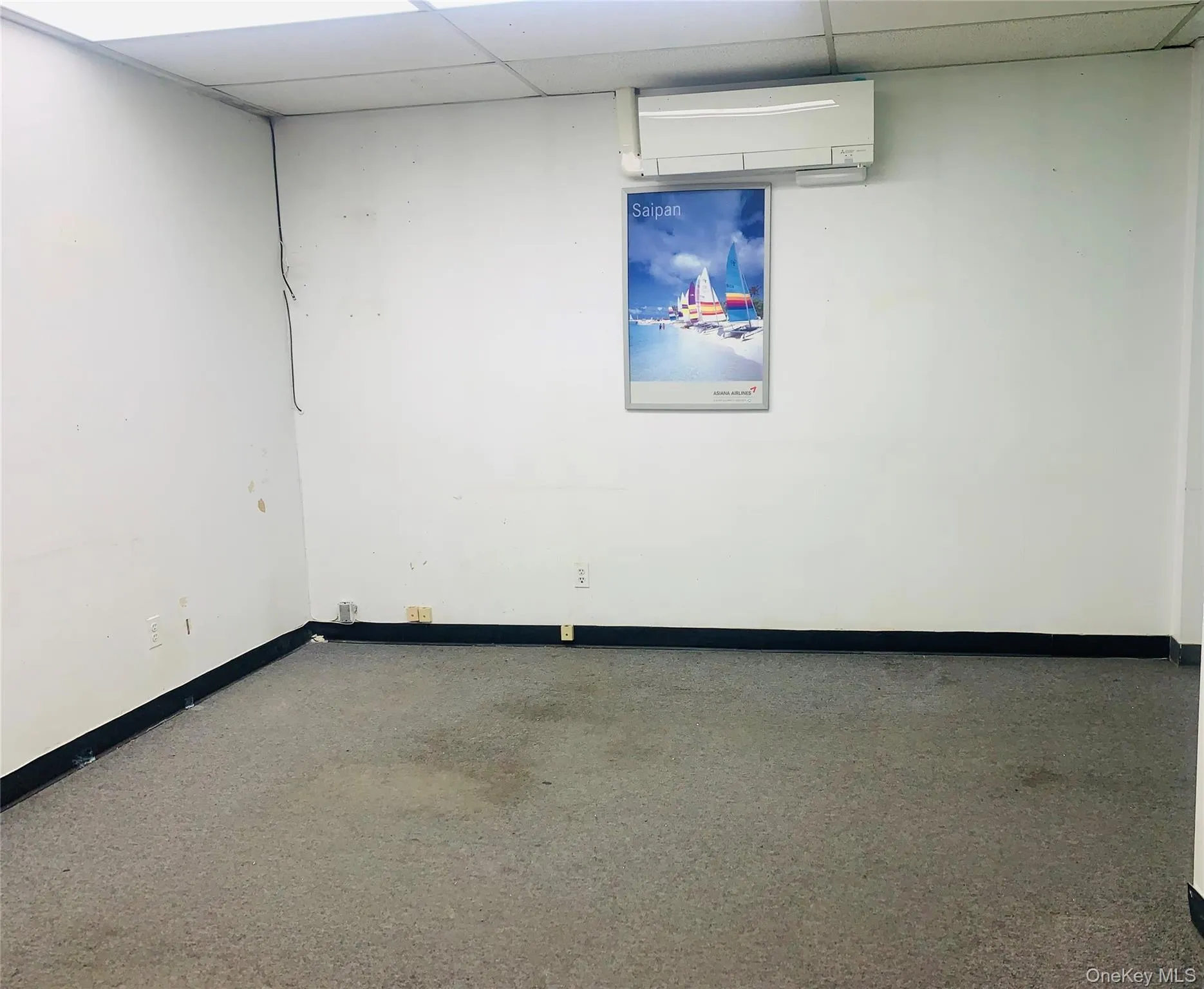 Empty room with baseboards, a paneled ceiling, and a wall mounted AC Empty room with baseboards, a paneled ceiling, and a wall mounted AC