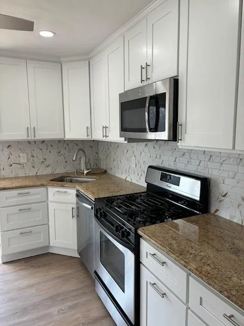 Kitchen with white cabinetry, stainless steel appliances, and a sink Kitchen with white cabinetry, stainless steel appliances, and a sink