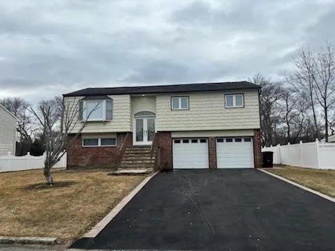 Raised ranch with a garage, brick siding, fence, driveway, and french doors Raised ranch with a garage, brick siding, fence, driveway, and french doors