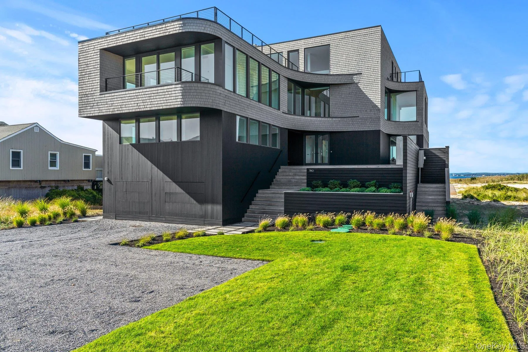 View of front of property featuring a balcony, stairs, and a front yard View of front of property featuring a balcony, stairs, and a front yard
