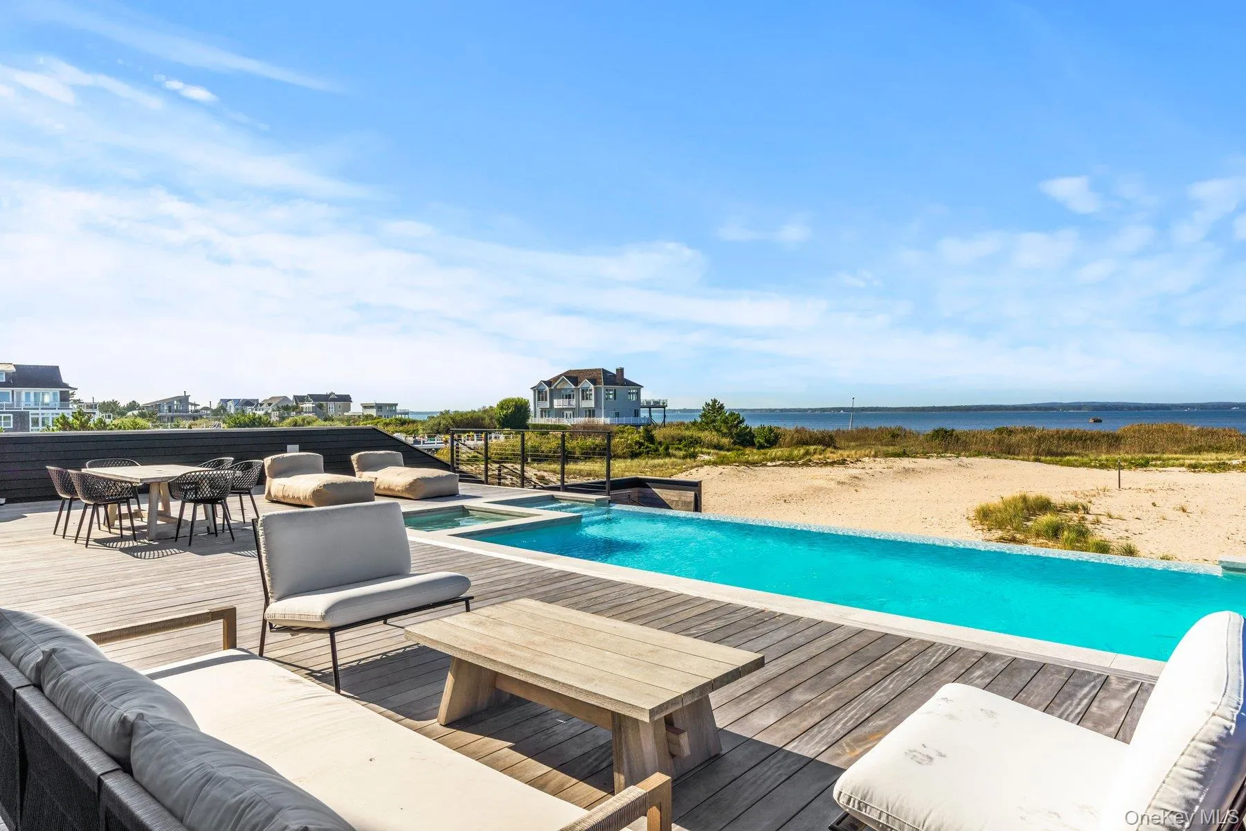 View of pool featuring a deck with water view, an outdoor hangout area, a pool with connected hot tub, and outdoor dining space View of pool featuring a deck with water view, an outdoor hangout area, a pool with connected hot tub, and outdoor dining space
