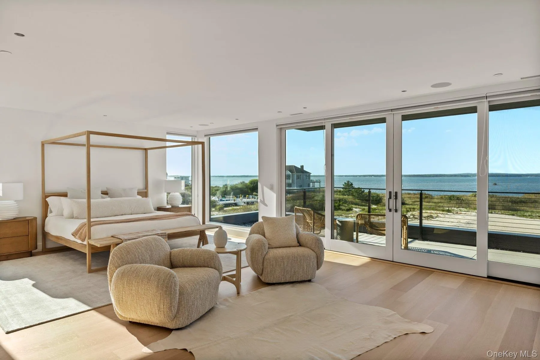 Bedroom with a water view, wood finished floors, access to exterior, and a wall of windows Bedroom with a water view, wood finished floors, access to exterior, and a wall of windows