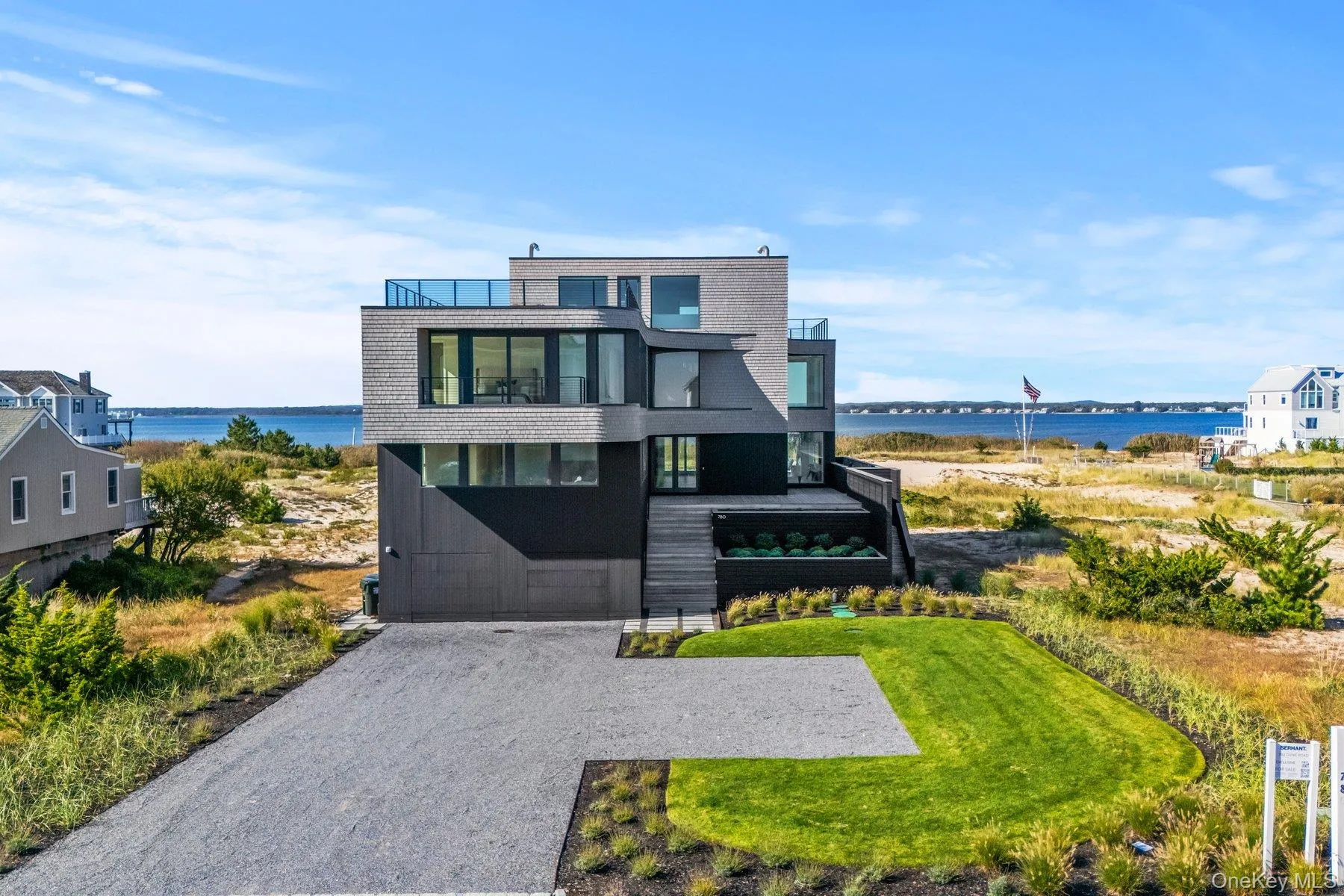 Contemporary house with a water view, a balcony, gravel driveway, and a garage Contemporary house with a water view, a balcony, gravel driveway, and a garage