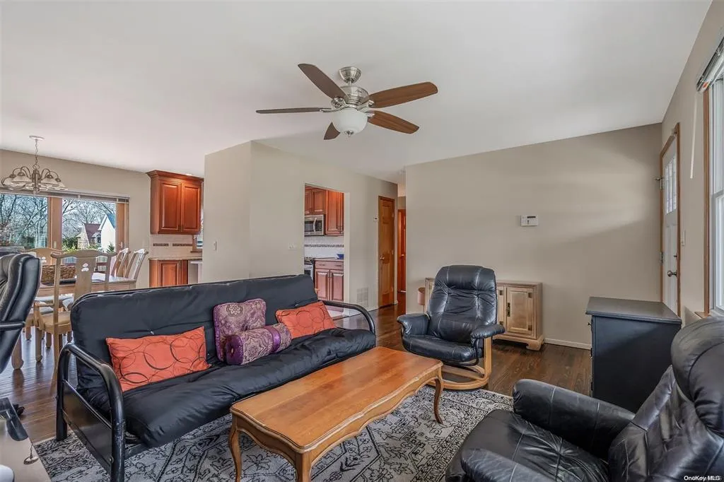 Living room with baseboards, dark wood finished floors, and ceiling fan with notable chandelier Living room with baseboards, dark wood finished floors, and ceiling fan with notable chandelier