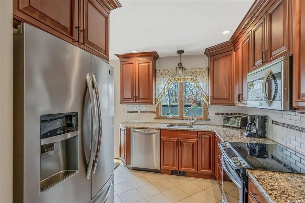 Kitchen with light stone counters, a sink, visible vents, appliances with stainless steel finishes, and tasteful backsplash Kitchen with light stone counters, a sink, visible vents, appliances with stainless steel finishes, and tasteful backsplash
