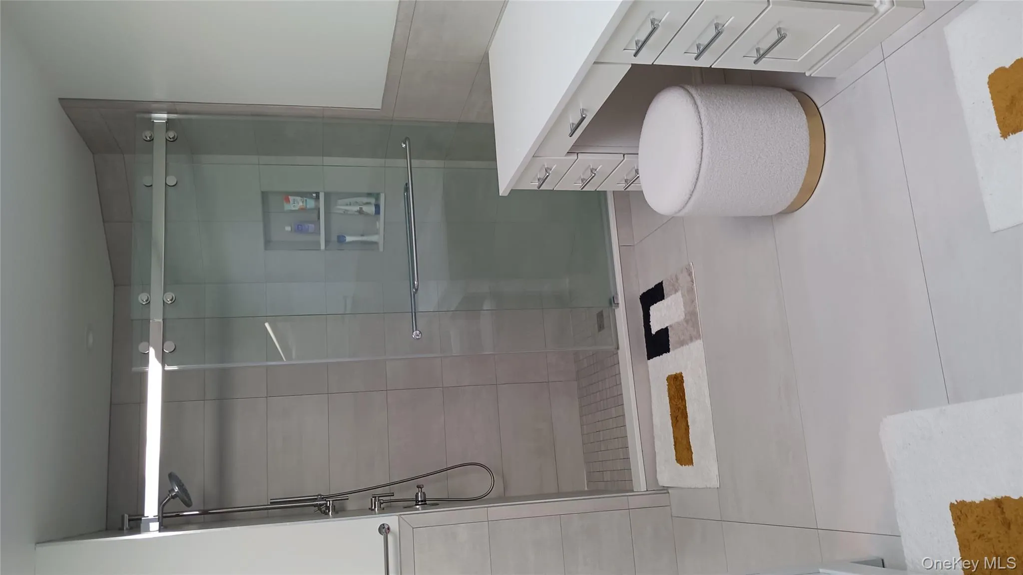 The heated floor primary bath features ,a make-up vanity, tile walls, and a shower stall The heated floor primary bath features ,a make-up vanity, tile walls, and a shower stall