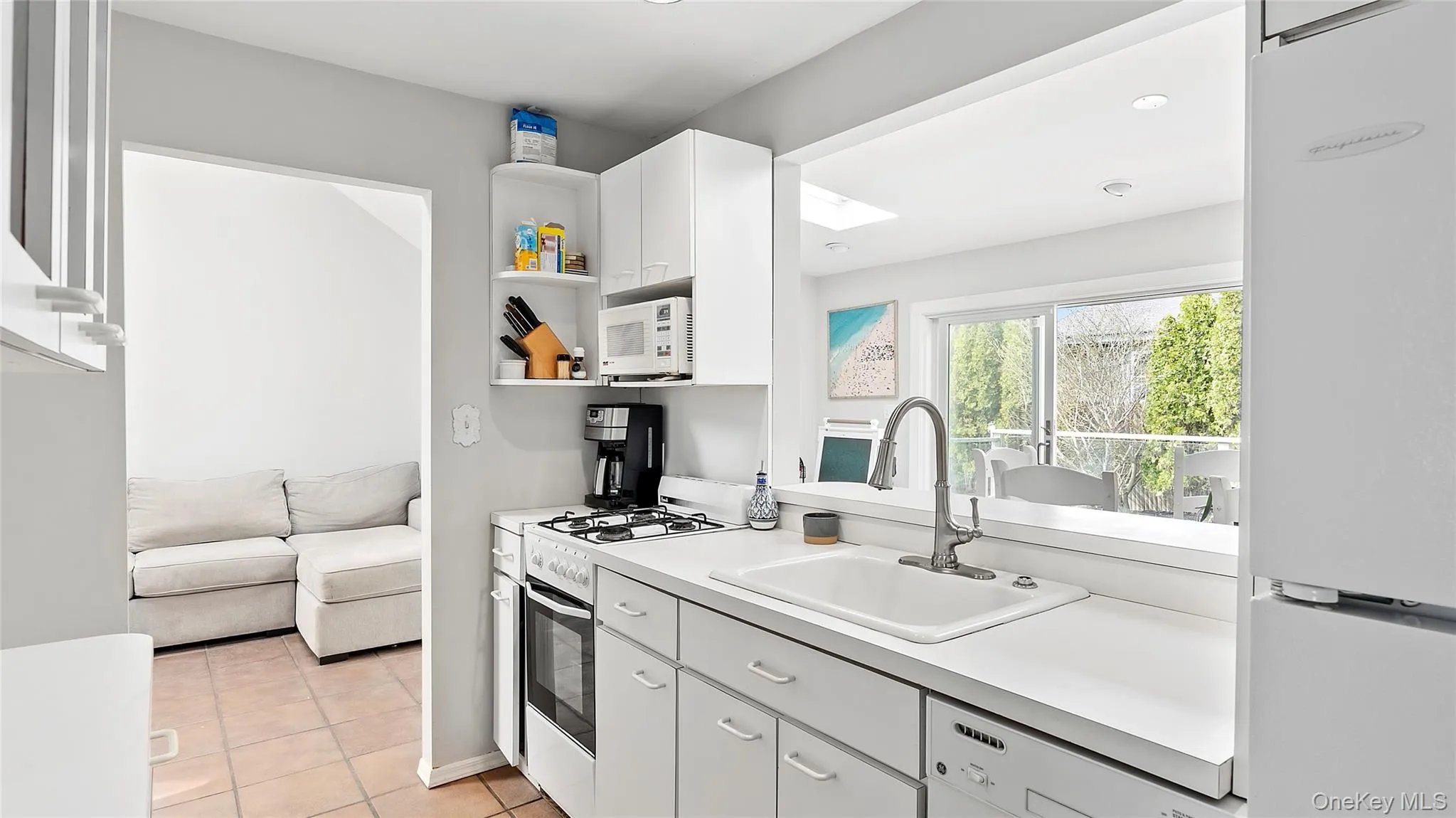 Kitchen with light tile patterned flooring, white appliances, a sink, white cabinets, and light countertops Kitchen with light tile patterned flooring, white appliances, a sink, white cabinets, and light countertops