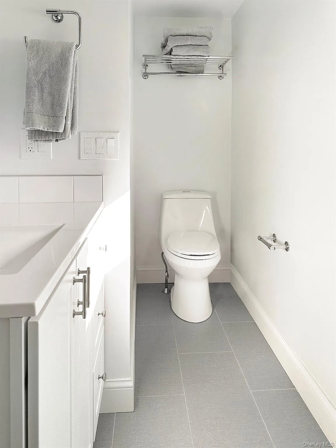 Half bath featuring toilet, tile patterned flooring, baseboards, and a sink Half bath featuring toilet, tile patterned flooring, baseboards, and a sink