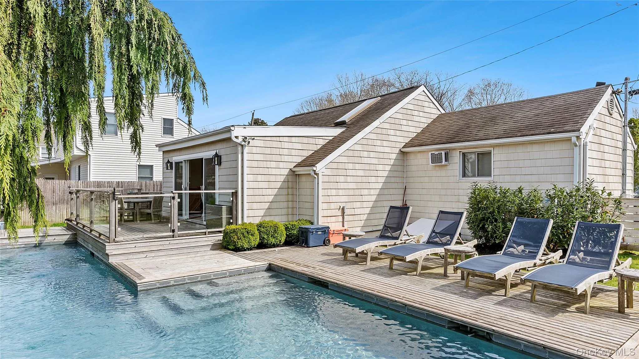 Rear view of house featuring a shingled roof, fence, a fenced in pool, and a wooden deck Rear view of house featuring a shingled roof, fence, a fenced in pool, and a wooden deck