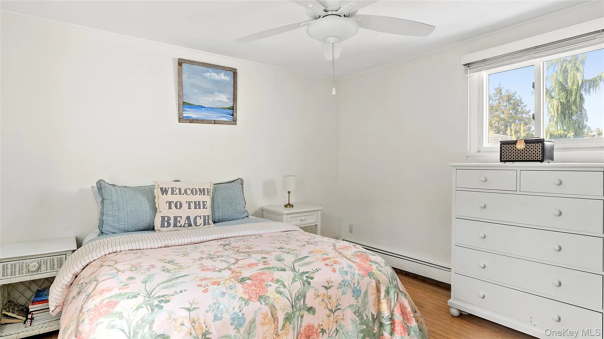 Bedroom featuring a baseboard heating unit, light wood-type flooring, and a ceiling fan Bedroom featuring a baseboard heating unit, light wood-type flooring, and a ceiling fan